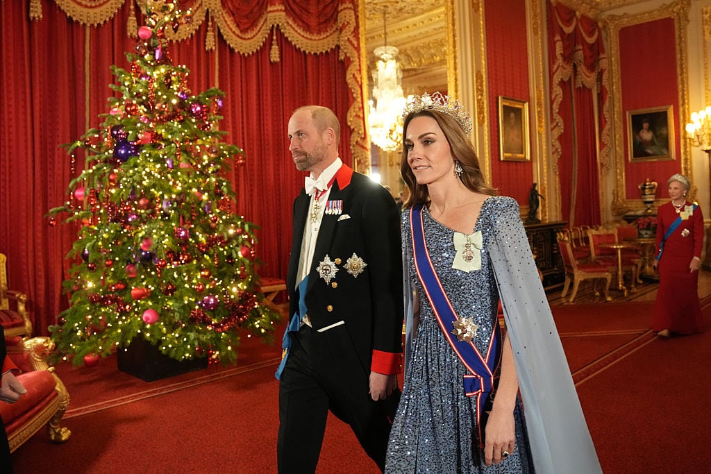 Two people walk by a Christmas tree.