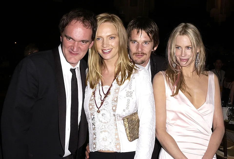 Four celebrities at an event. The men wear suits; one woman wears an ornate top with a clutch, and the other a flowing dress
