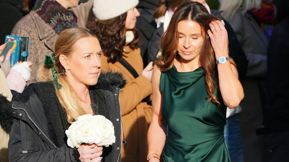 Holly's mother Ramsay was pictured entering the venue in a floor length emerald green gown. She is touching her brown hair with her hand. A woman to her left is pictured holding a bouquet of flowers.