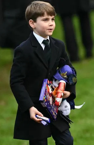 OLI SCARFF/AFP via Getty Prince Louis carries gifts from well-wishers after attending Christmas Day service at St. Mary Magdalene Church on Dec. 25, 2024.