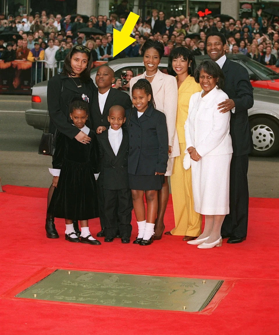 Group of people posing together on a red carpet event, with children dressed in formal attire and adults in elegant suits and dresses