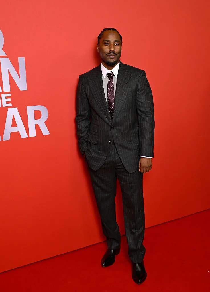 Person in a pinstripe suit poses on the red carpet at a formal event