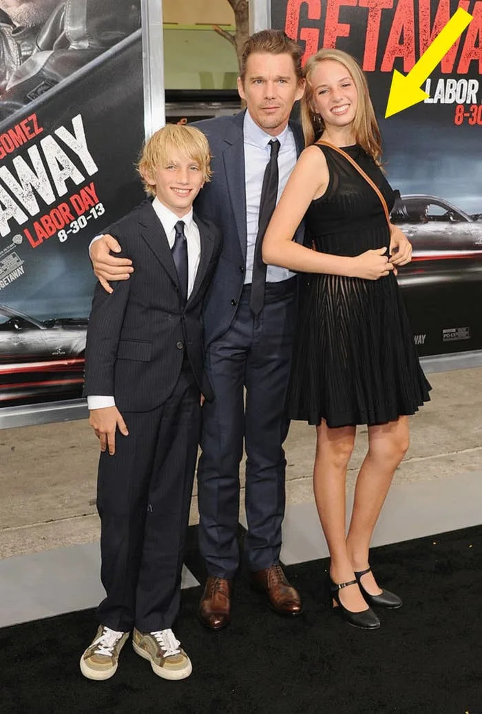 A man in a suit poses with a young boy in a suit and a girl in a pleated black dress at a red carpet event for "Getaway."