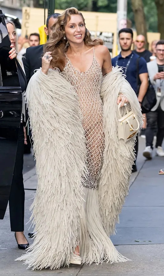 Miley Cyrus at the Tribeca Film Festival wearing a sheer embellished dress layered with a textured outer piece