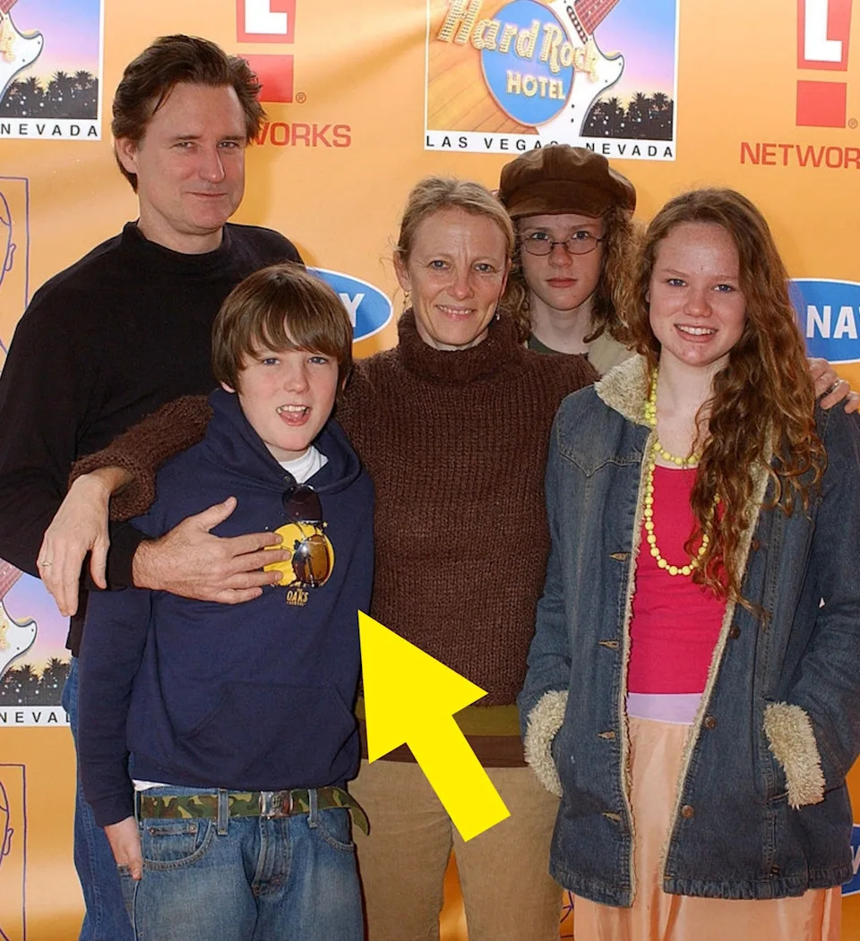 Six people stand together smiling at a media event, posed in front of a branded backdrop