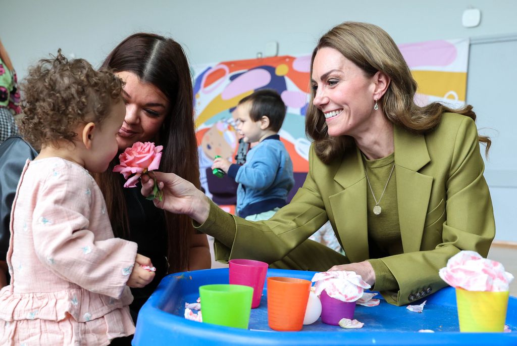 Kate holding a flower and smiling at little girl