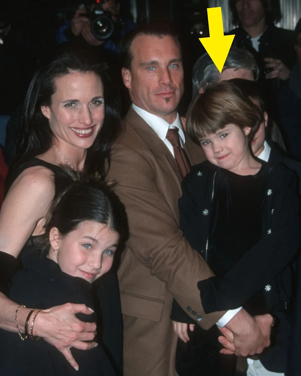 A family posing together on a red carpet, surrounded by photographers. Adults in formal attire; children smiling in dark outfits