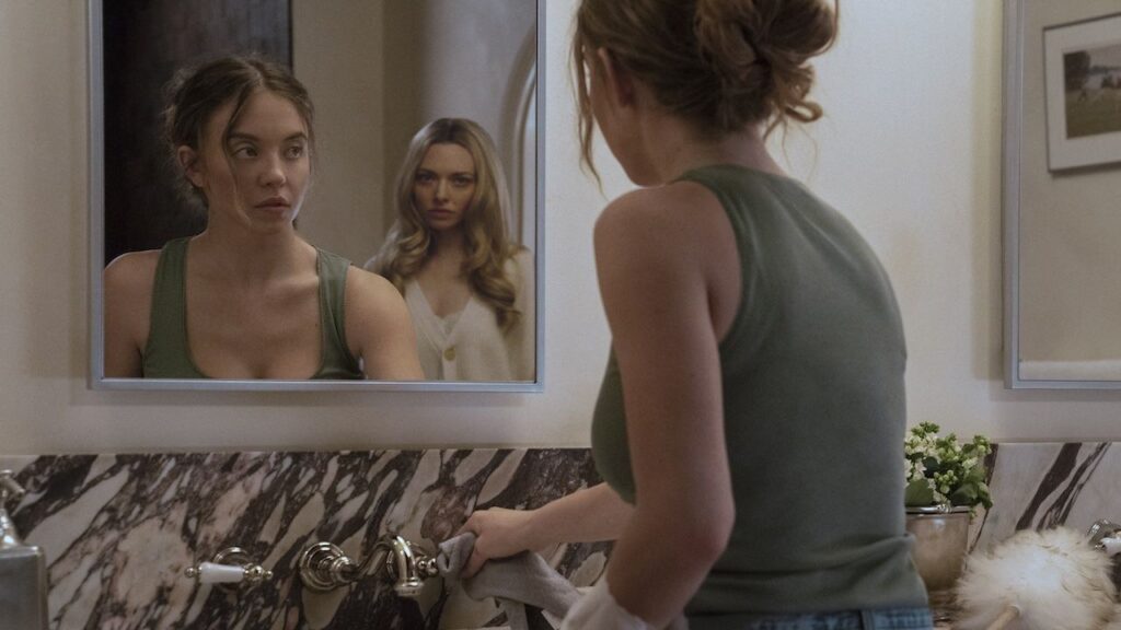 I Can’t Get Over The Housemaid Movie’s Punny 3-Word Response To Sydney Sweeney And Amanda Seyfried Rocking The Red Carpet In Plunging Dresses Sydney Sweeney standing at the mirror with Amanda Seyfried behind her in The Housemaid