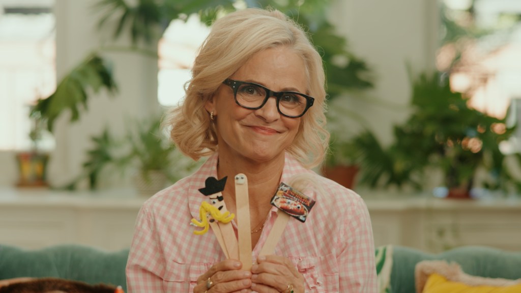 Amy Sedaris holding crafts made from popsicle sticks.