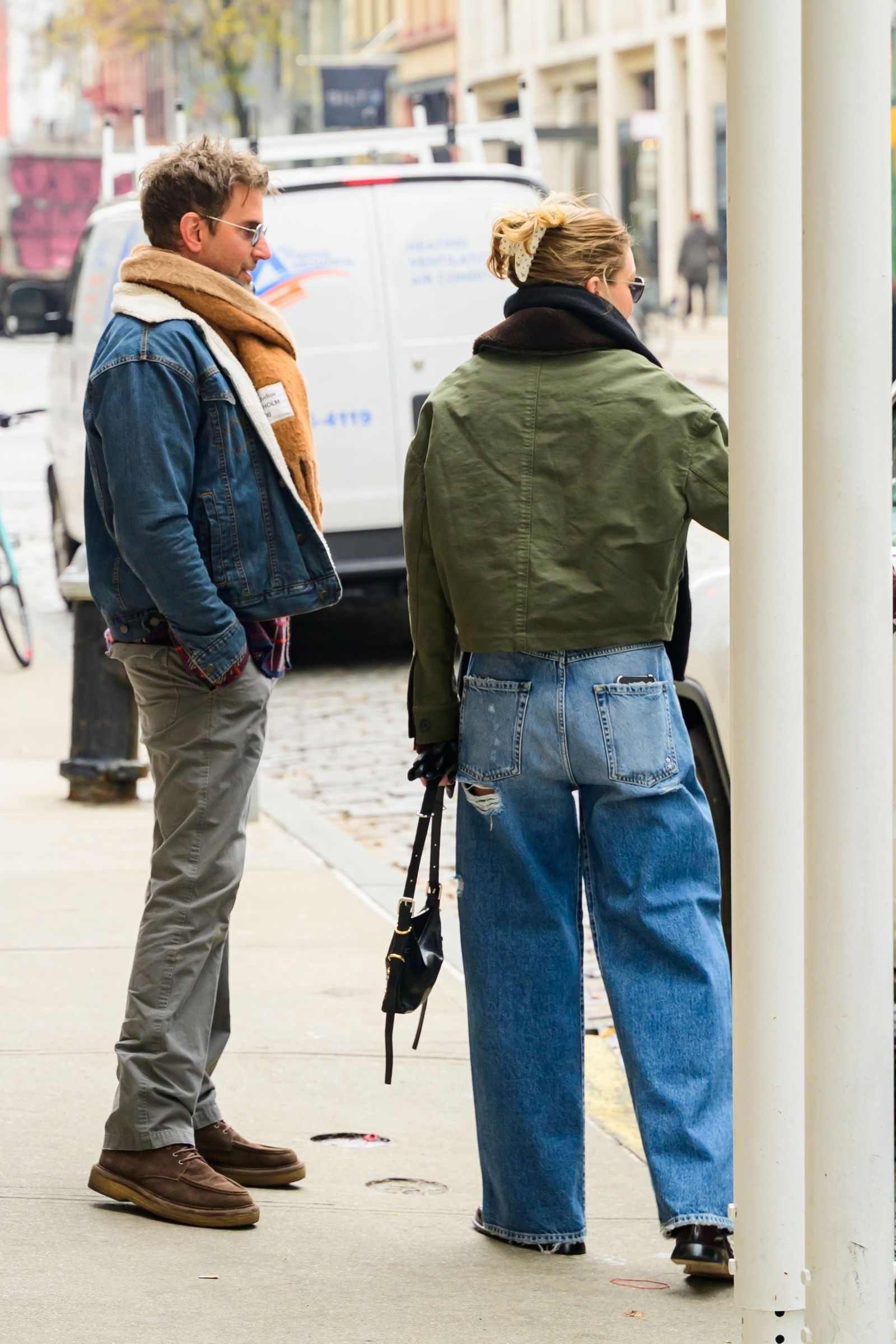 Image may contain Bradley Cooper Clothing Pants Coat Jeans Person Accessories Bag Handbag Adult Footwear and Shoe