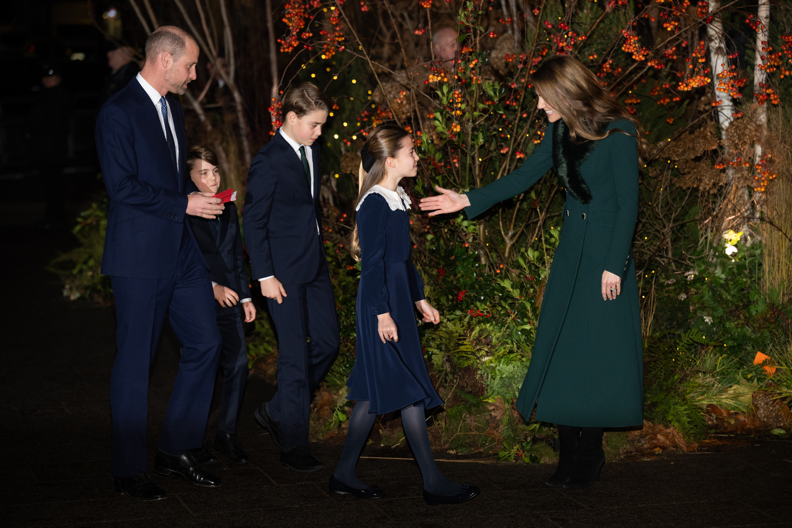 Princess Kate greeting Princess Charlotte at the Together at Christmas concert, with Prince William, Prince George and Prince Louis walking behind