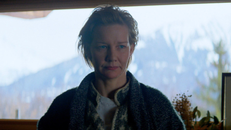 Sandra Huller as Sandra Voyter in front of a window looking out on a snowy mountain in Anatomy of a Fall