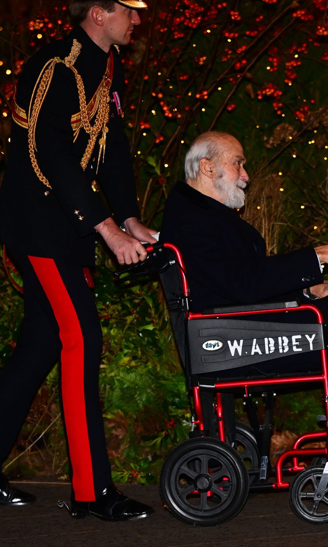 A man pushing Prince Michael of Kent in a wheelchair