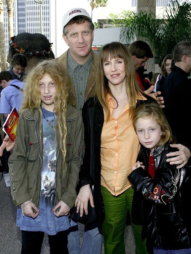 A family poses together at an outdoor event. The adults wear casual jackets, and the children are in relaxed attire