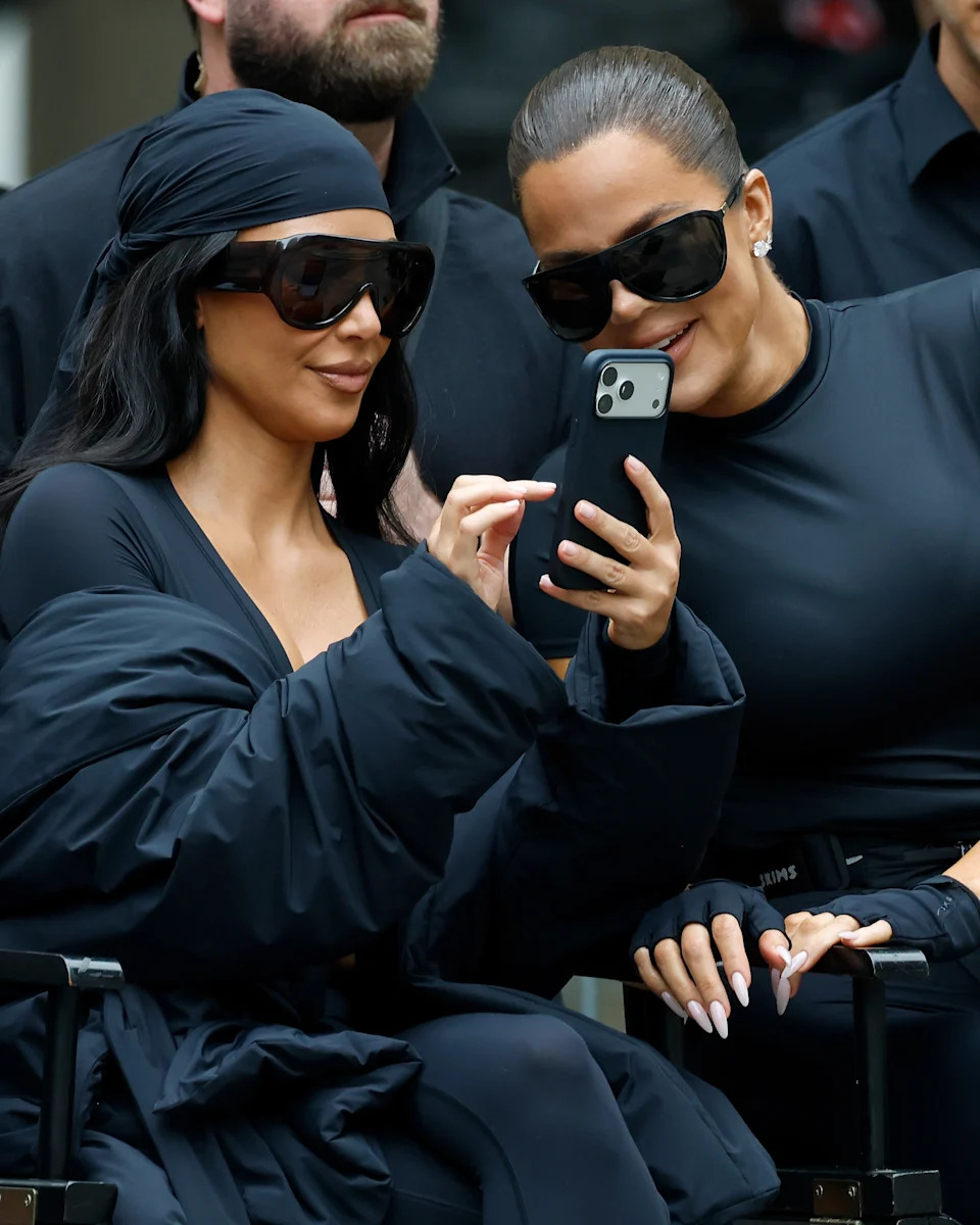 Kim Kardashian shows Khloe Kardashian something on her phone