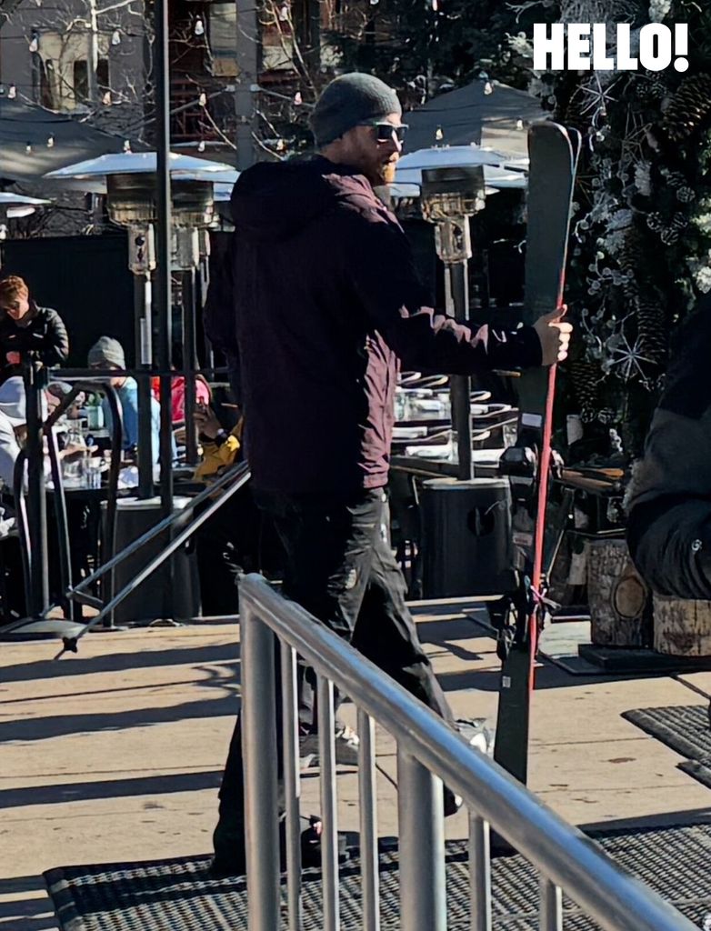 Prince Harry wearing beanie hat and carrying skis