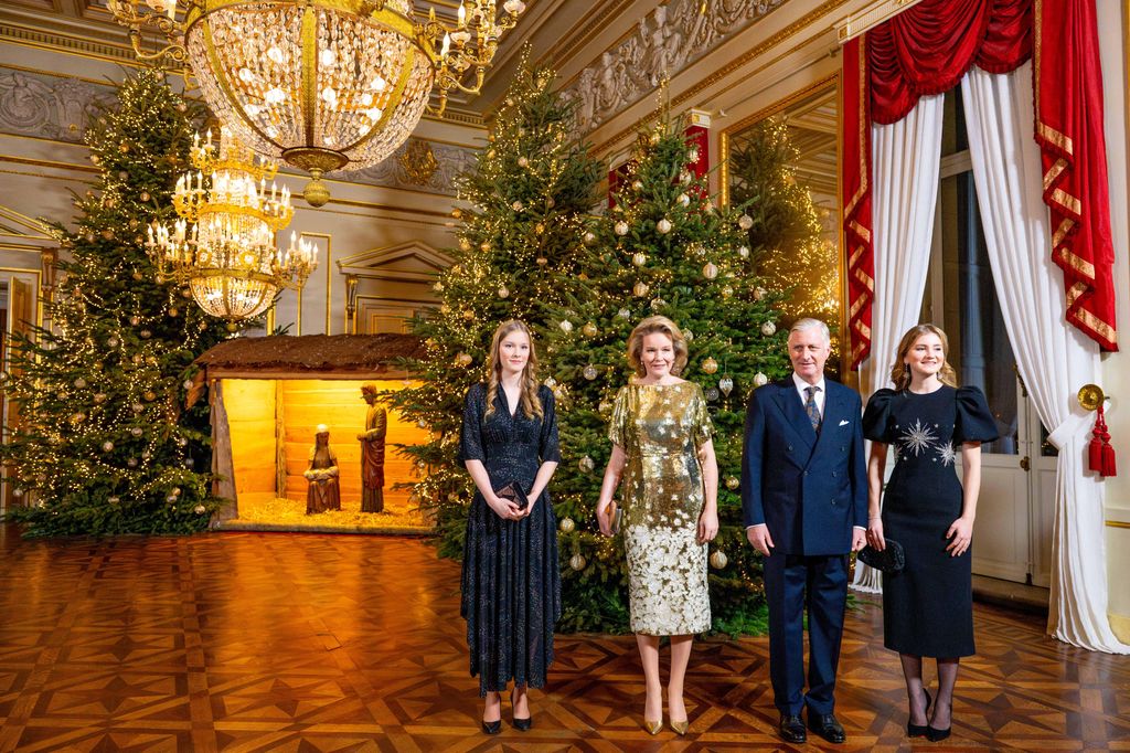 Princess Eleanore, Queen Mathilde, King Philippe and Princess Elisabeth standing in front of three Christmas trees