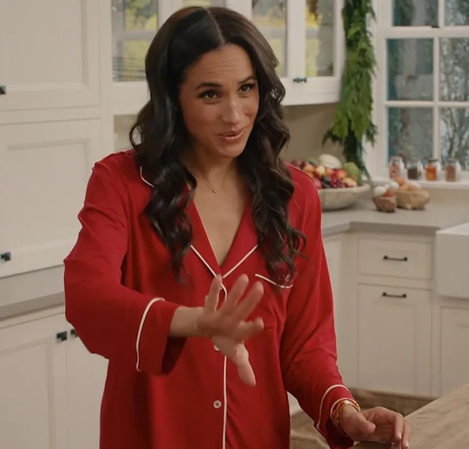 Meghan Markle wearing festive red Eberjey pajamas with white piping in a white kitchen during her Netflix holiday special.