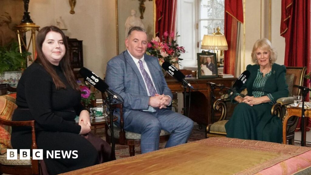 Queen praises Hunt family for their bravery after triple murders Amy Hunt, a woman with brown hair wearing a black long sleeved dress, and John Hunt wearing a grey checked suit sit with Queen Camilla who wears a dark green outfit. Baroness Theresa May and Emma Barnett were also sat around a table in Clarence House but out of shot.