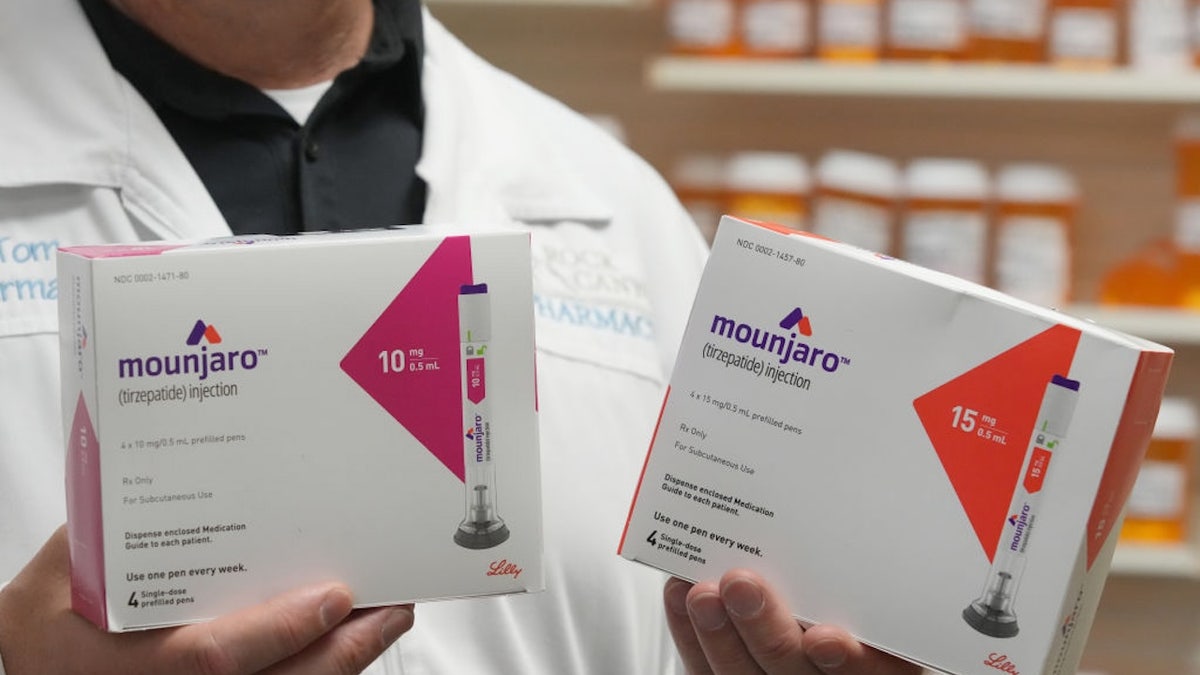 pharmacist holds up two boxes of Mounjaro