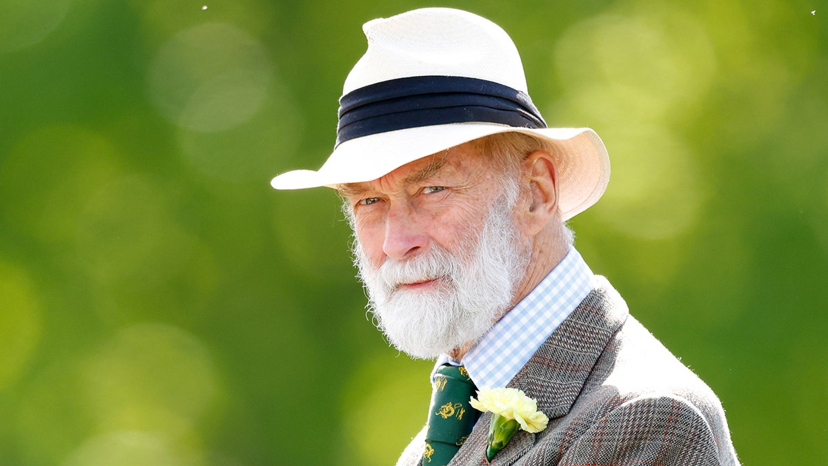 Michael of Kent in a grey suit and white fedora.