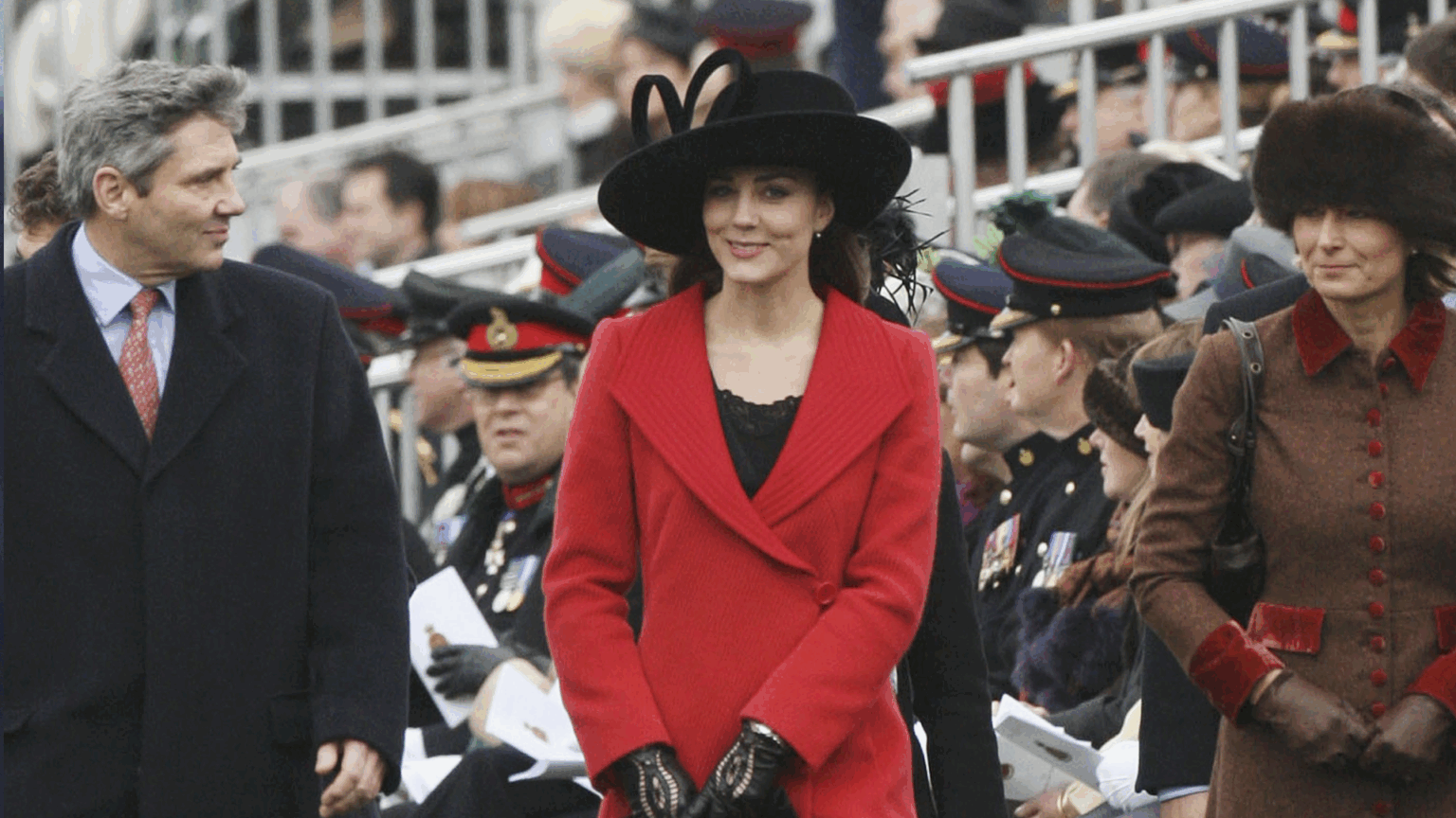 Kate Middleton wearing a red coat and black hat next to her parents