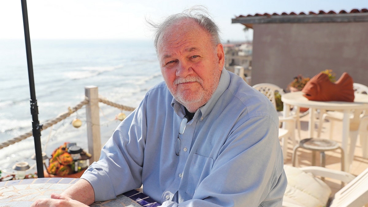 Thomas Markle wearing a light blue shirt as he sits by the beach.