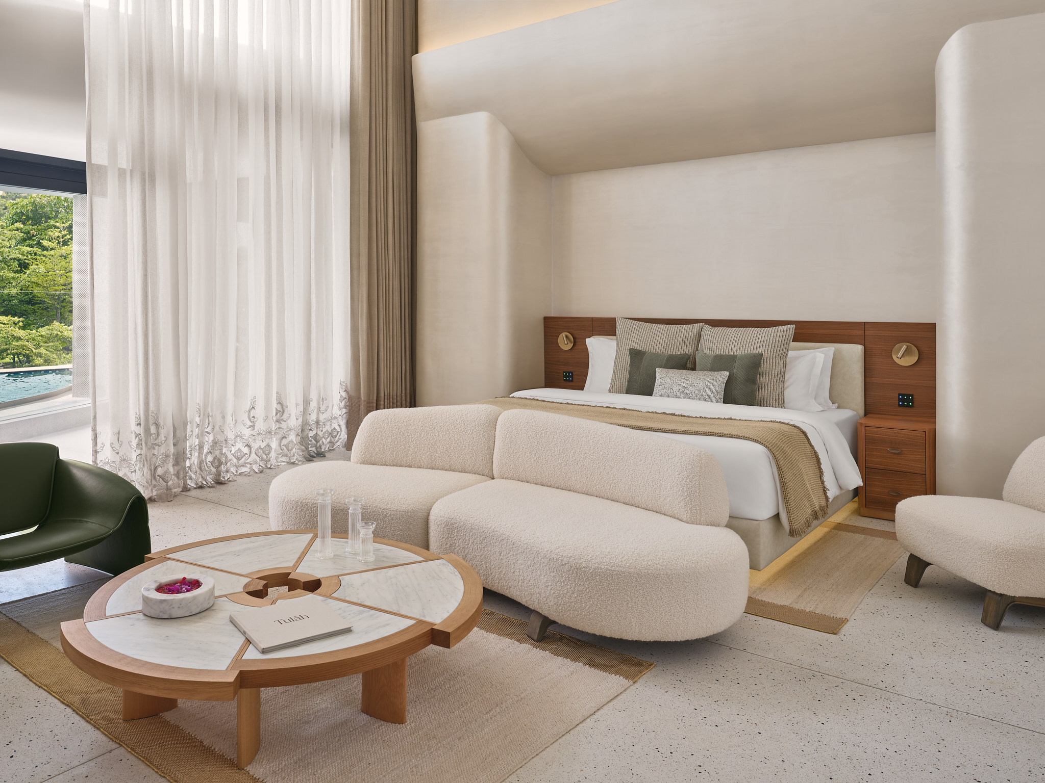 Tulah hotel room interior in India with a king bed, curved sofa, and marble coffee table.