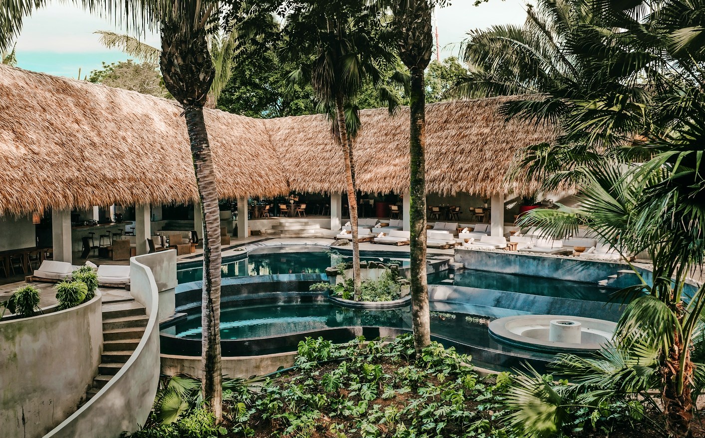 ESH Hotel in Costa Rica with a thatched roof, swimming pool, and tropical plants.