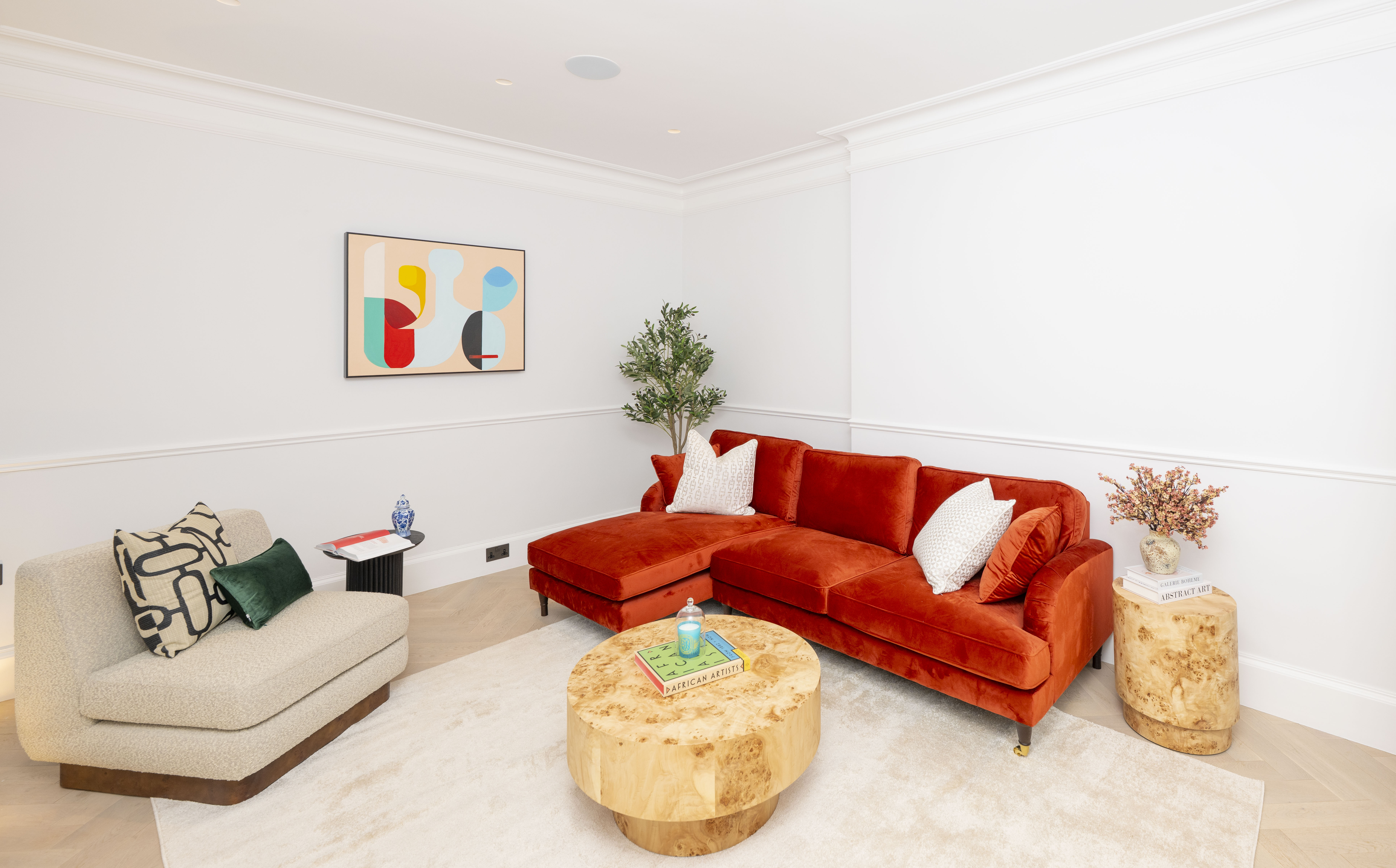 Interior view of a living room with an orange sectional sofa, a beige armchair, and a wooden coffee table.