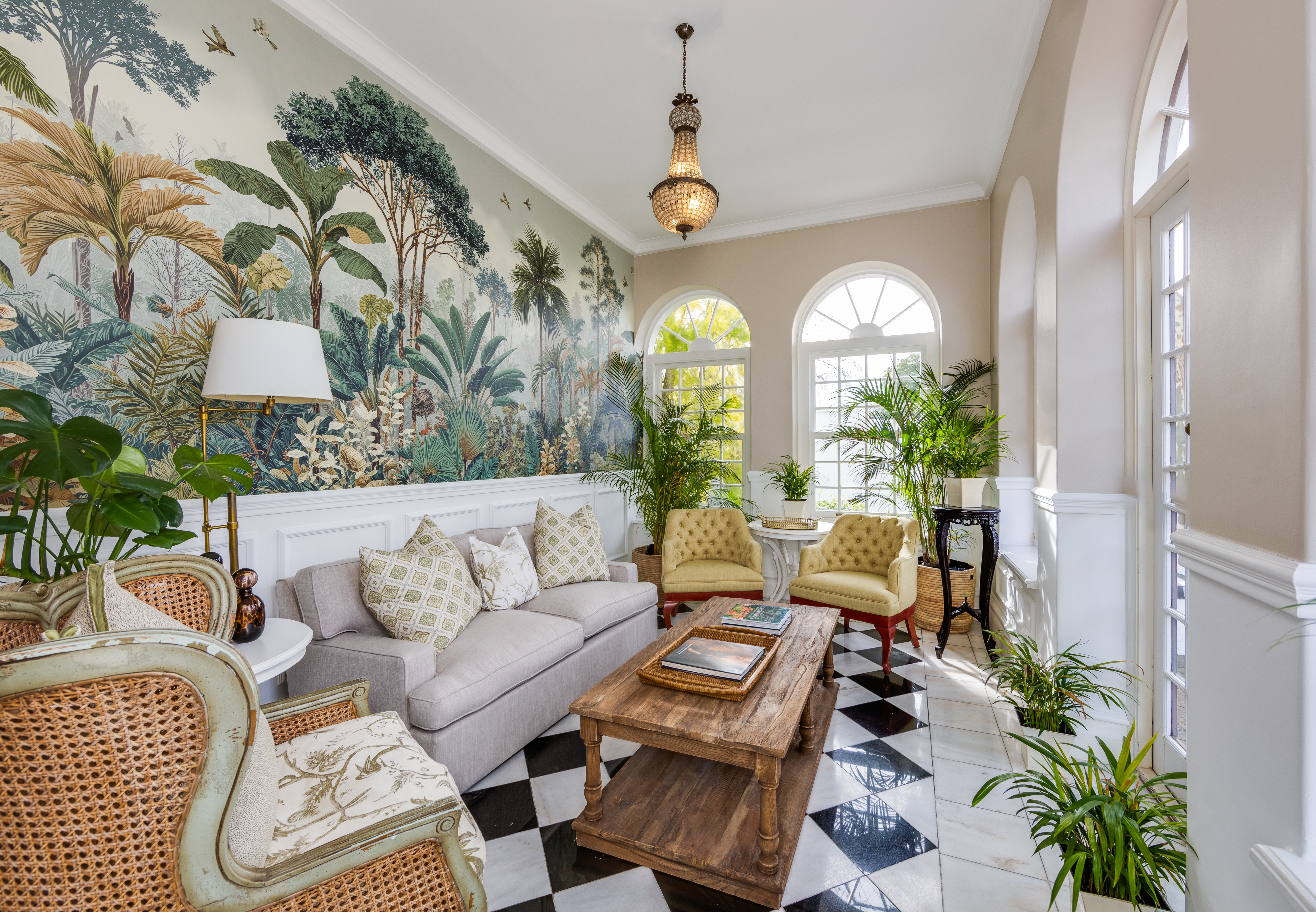 The Claremont Hotel sun lounge with a black and white checkered floor, tropical wallpaper, and multiple arched windows.