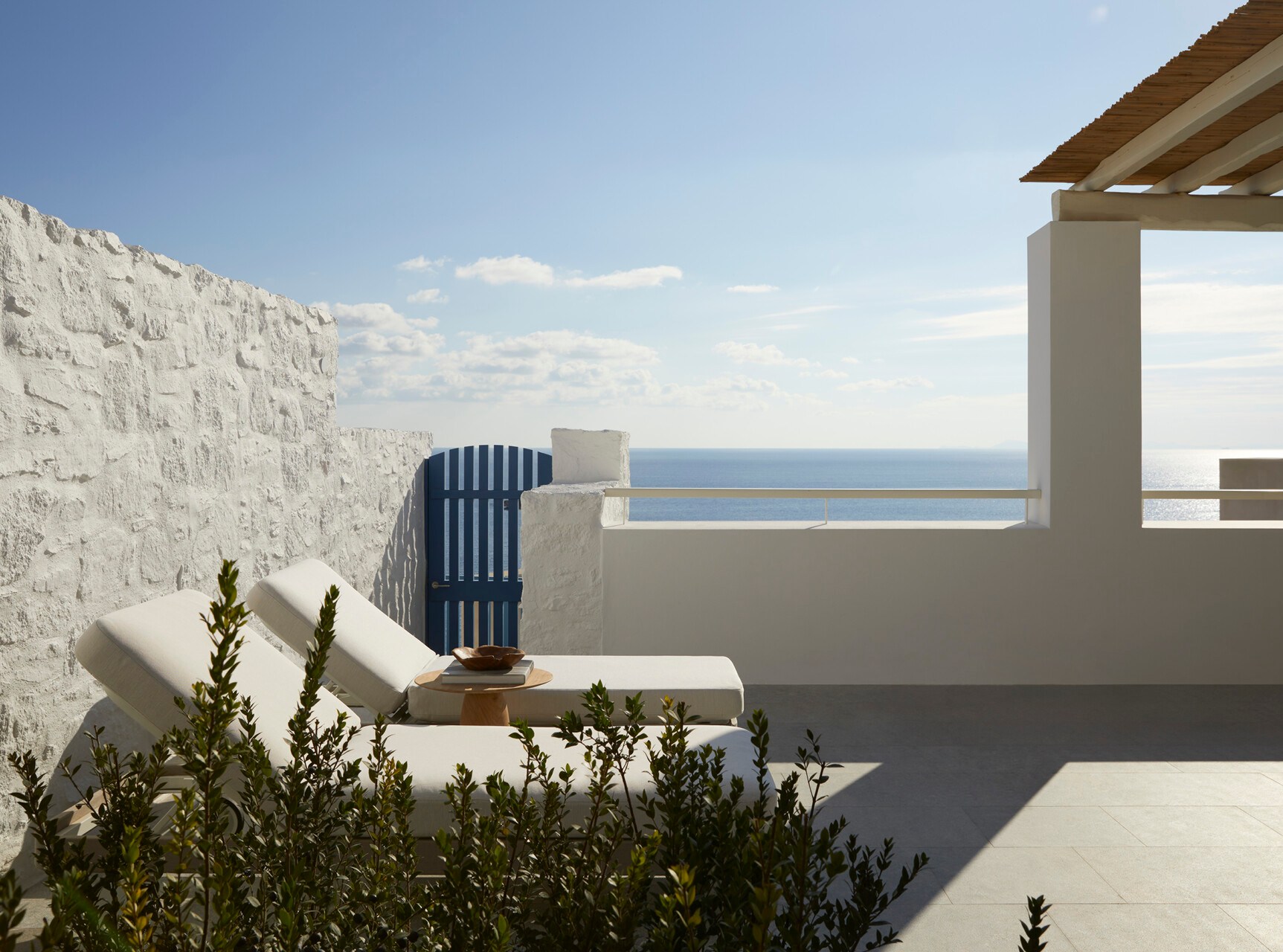 Terrace at Four Seasons Resort Mykonos with two lounge chairs overlooking the sea.