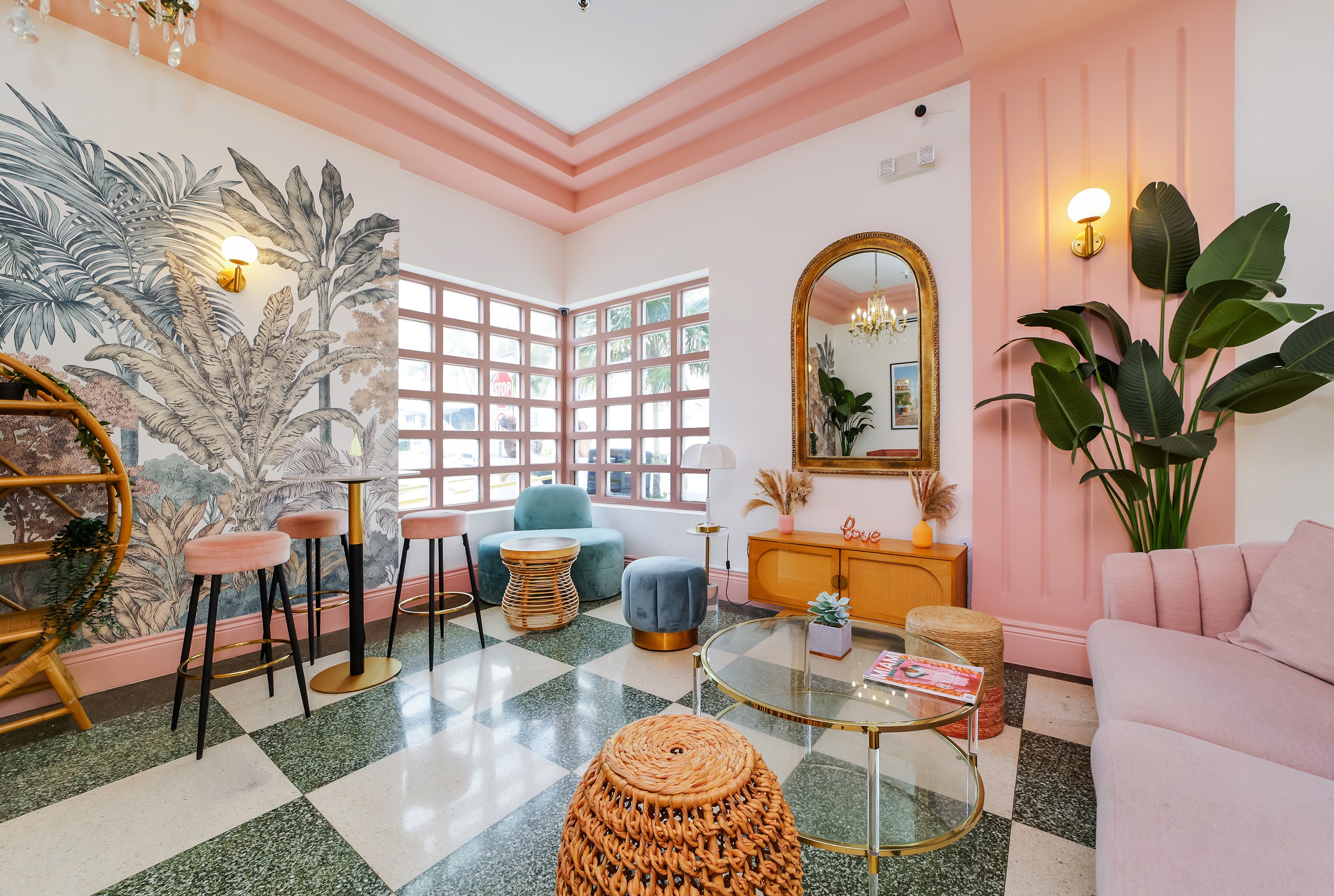 Lobby of Le Particulier in Miami with pink walls, tropical wallpaper, and checkered floors.