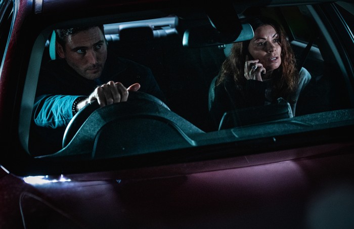 05_01_CORRIEDALE_KIT_CARLA_CAR Kit drives a darkened car as Carla, in the passenger seat, uses her phone in a scene from Corriedale