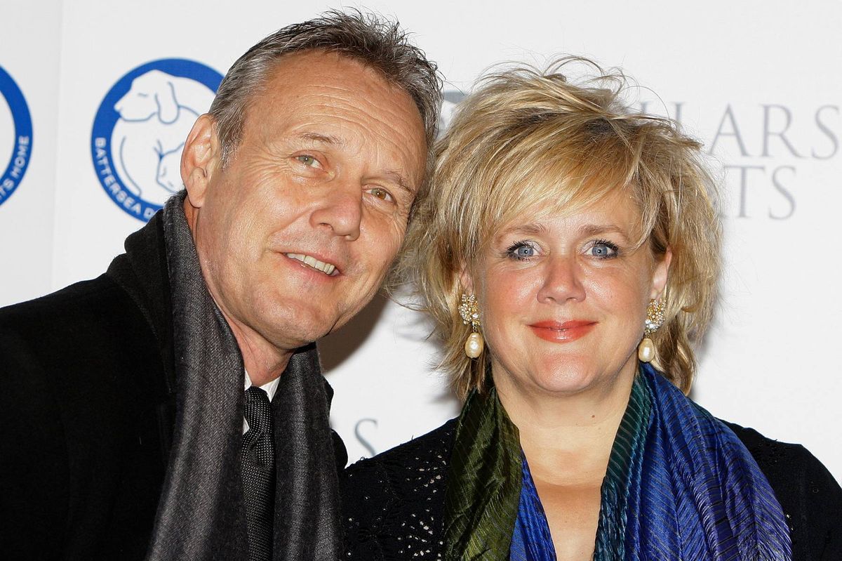 An adult male and female, both dressed in winter attire, are standing close to each other, posing for a photograph against a backdrop with text and logos.