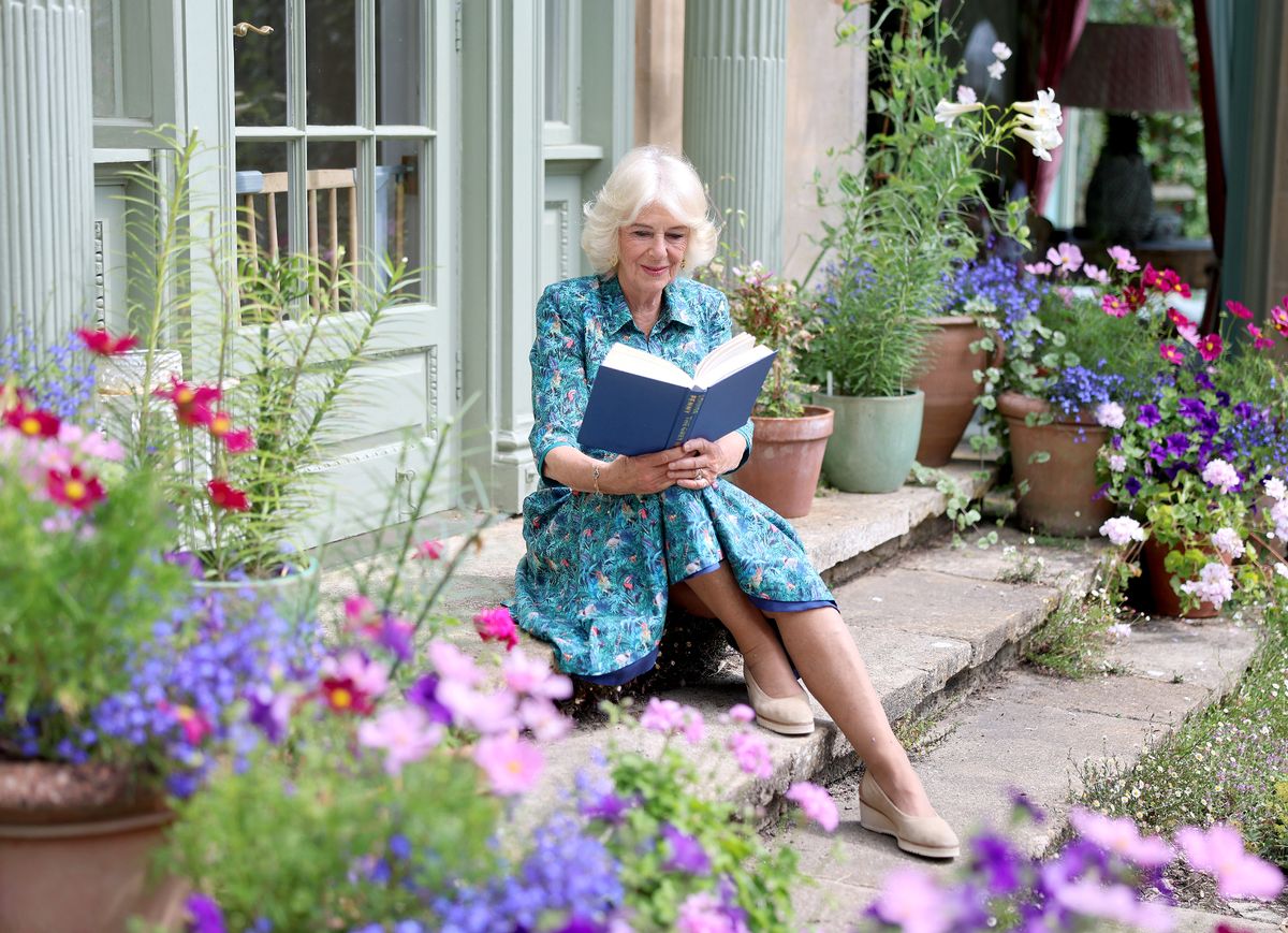 A new image of Queen Camilla reading a book in the garden of her home Ray Mill House in Wiltshire last July 