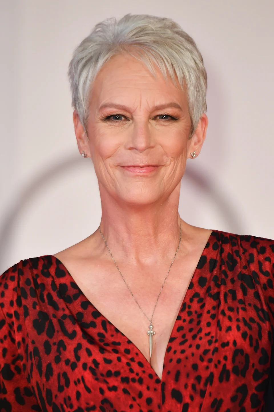 Person with short hair in elegant leopard-print outfit and subtle necklace at an event