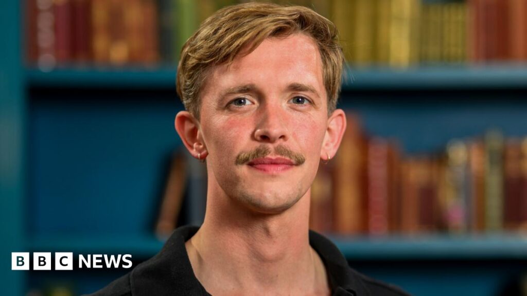Stephen from The Traitors: ‘I’m proud to be from Lewis – but I couldn’t tell anyone the result’ Stephen Libby, a man with blonde hair and a well groomed moustache standing on a grand outdoor staircase, which he is leaning on with his left arm. He is wearing a striking black jumpsuit with a deep v-neck and white binding down the sides.