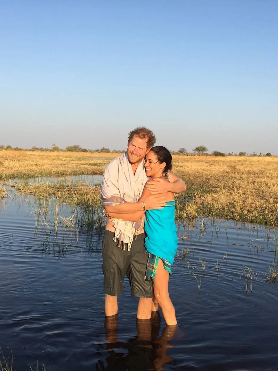 Couple standing in water in a grassy landscape
