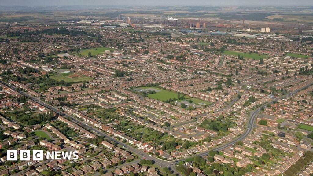 Aerial view of houses in Scunthorpe with smoke rising from the chimneys of the town's steel mill in the background