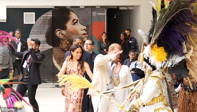 Footage showed how, at one point, a dancer's costume nearly hit Prince Harry, 41, on the head. Meghan then appeared to try and get Harry's attention with an 'arm-steering ritual' (pictured)