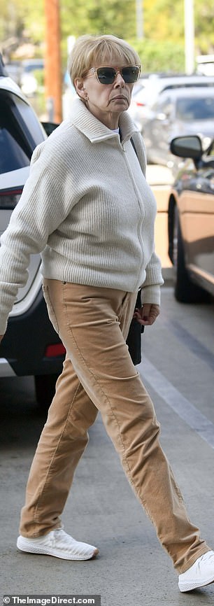 She kept it casual in a cream zip-down sweater and brown slacks