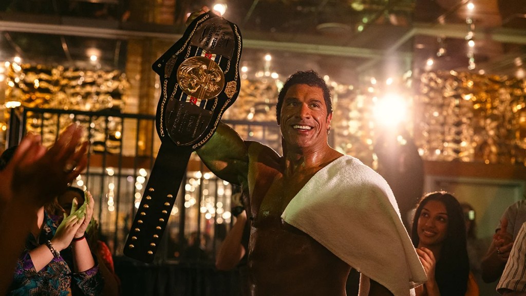 Dwayne Johnson holds up a championship belt in "The Smashing Machine"