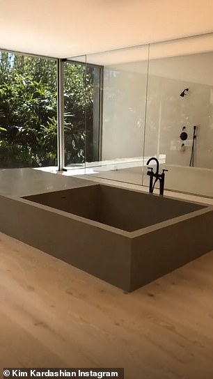 The bathrooms in the massive home features very little furniture with a modern bathtub and floor to ceiling windows that reveal the foliage outside