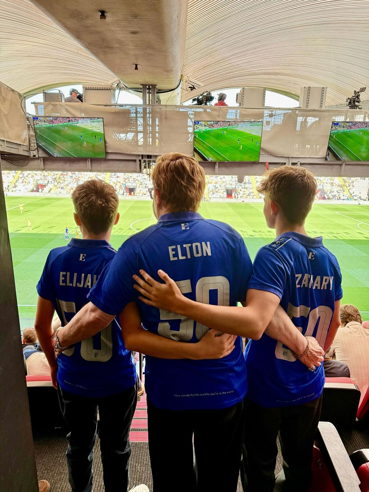 elton john with boys from behind at a watford fc match