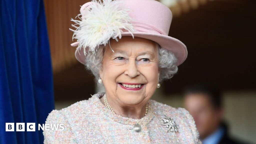 Queen Elizabeth II is seen in a pink hat smiling during an appearance at the Chichester Theatre