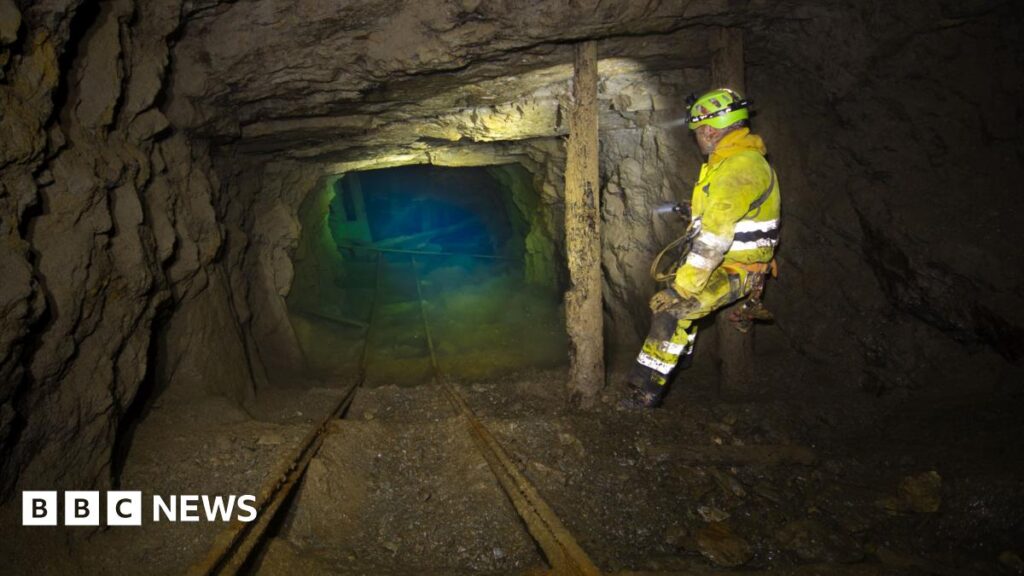 Documentary about Cornwall mine explorers set for national tour A man is a yellow boilersuit stands in an old mine working, the rocky tunnel ends in a green blue pool of water