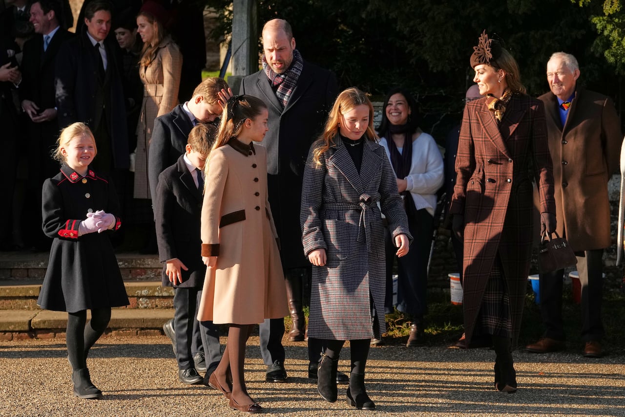 Several people walk together on a gravel area near a church.