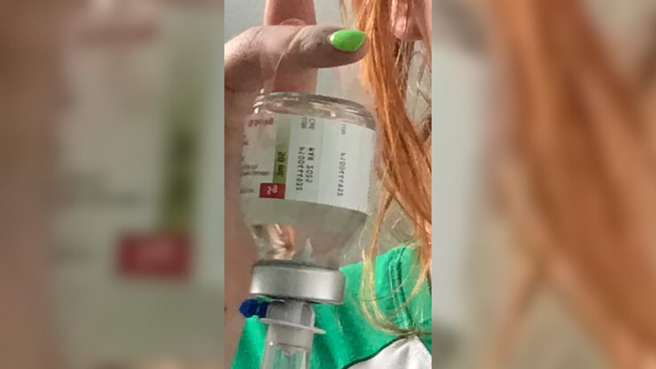 A close up of a blood product bottle by held up by a finger.