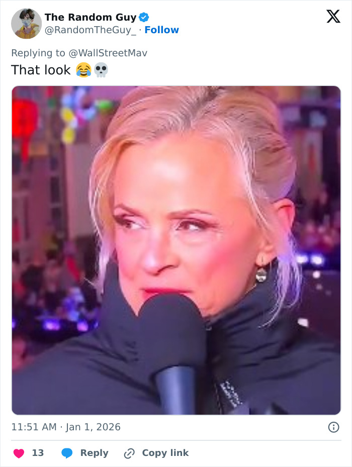 Amy Sedaris speaking into a microphone during CNN's New Year's Eve broadcast, with a blurred festive background.